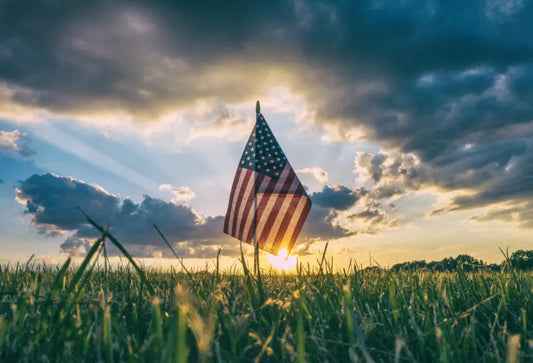 Old Glory American Flag flying over wheat field with nice lighting coming through clouds