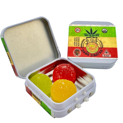 Open tin containing colorful gummy bears with a cannabis product label in the background.