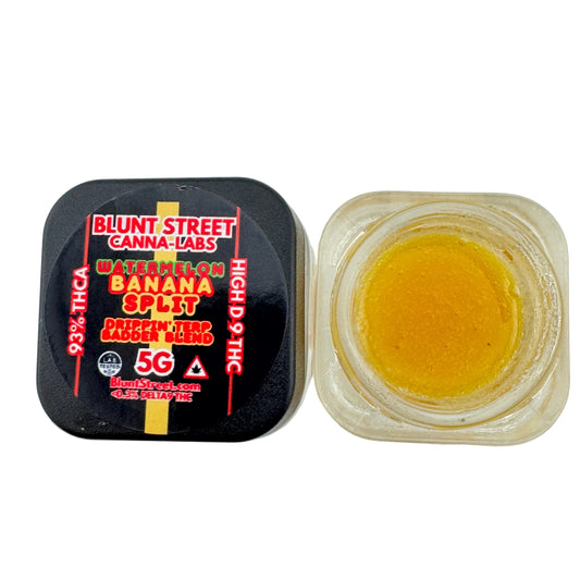 Jar of yellow substance next to a black container labeled 'Blunt Street Canna Labs' on a white background