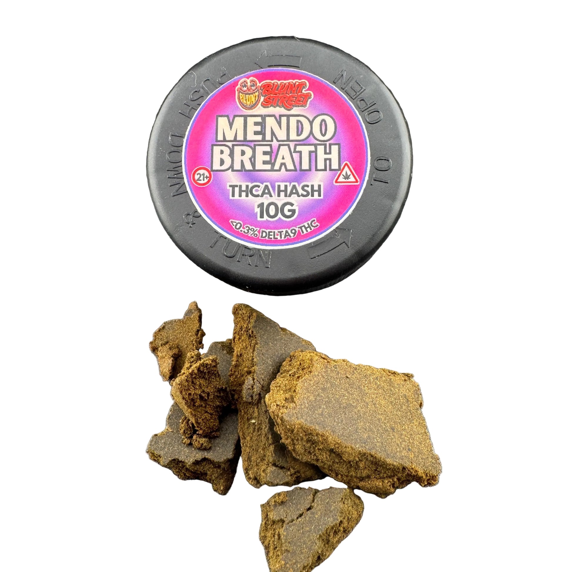 A black round tin labeled 'MENDO BREATH' with a pink and purple label, shown on a dark gray surface with several broken brownish-green hash crystals in front.