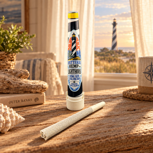 A pre-rolled cone of white hemp material lies horizontally below a tall cylindrical tube labeled 'Matteras Hemp Lighting Pre-Roll'. The tube features a black and white striped lighthouse design with a yellow cap, set against a plain white background.