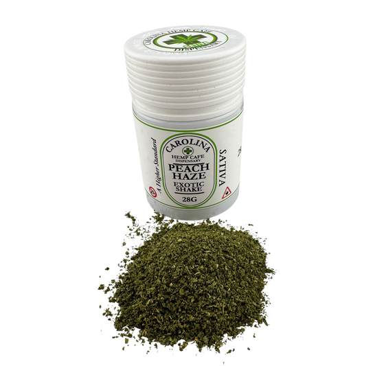 A small white plastic jar labeled Carolina Valley Hemp Cafe Peach Haze Exotic Snake, shown with a pile of dried green herb below on a white background.