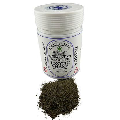 A white plastic jar of Carolina Hemp Cafe Exotic Shake Permanent Designer with a white lid, shown with a small pile of dark green herbal powder in front on a white background.